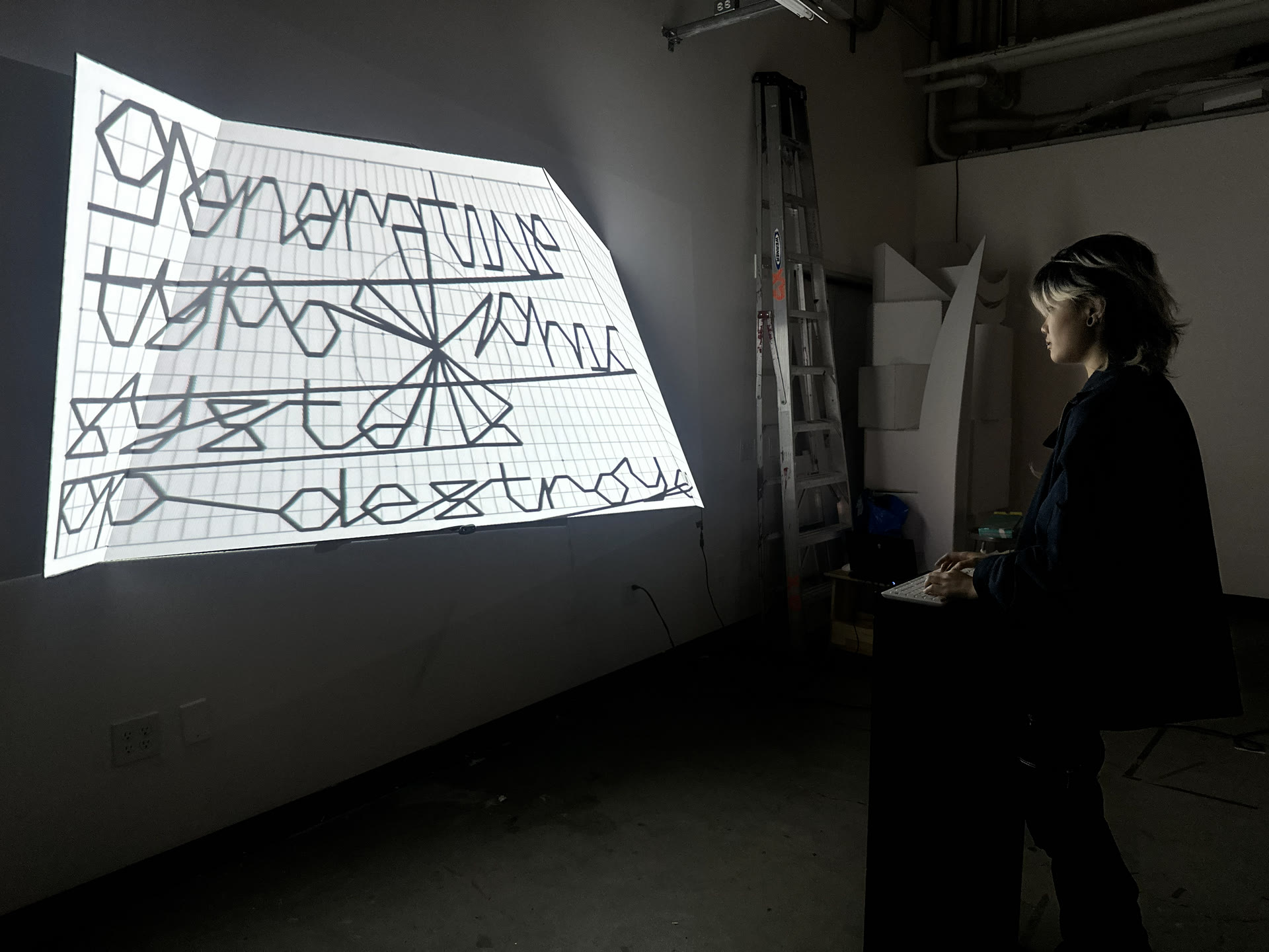 Generative type projected on the folded wall, with a visitor at the controls